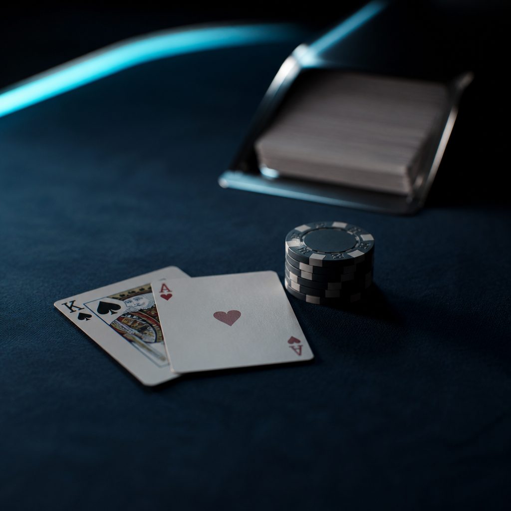 Zwei aufgedeckte Spielkarten und ein kleiner Chipstapel auf dunkelblauem Filz eines Blackjack-Tischs